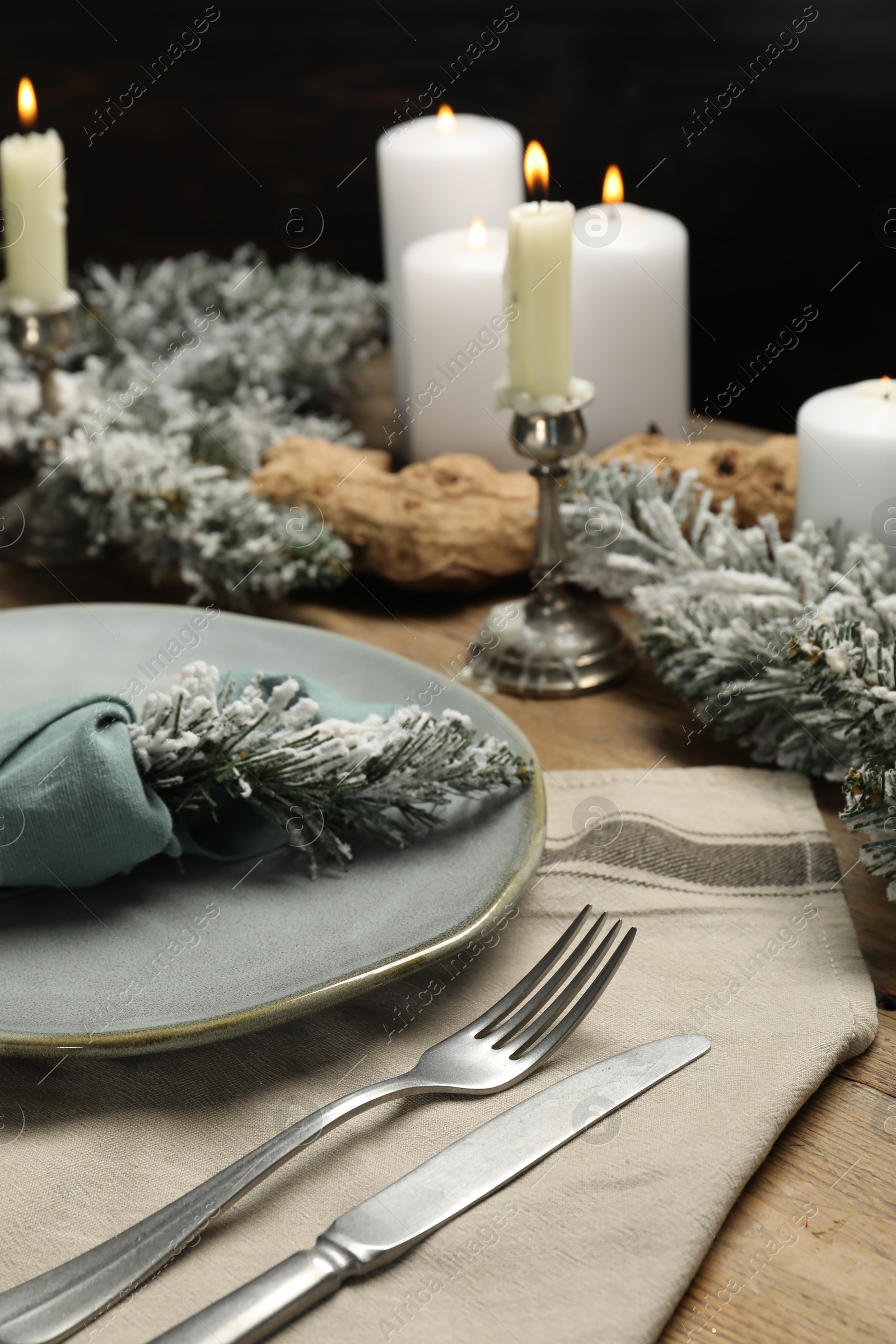 Photo of Plate, cutlery and Christmas decor on wooden table, closeup