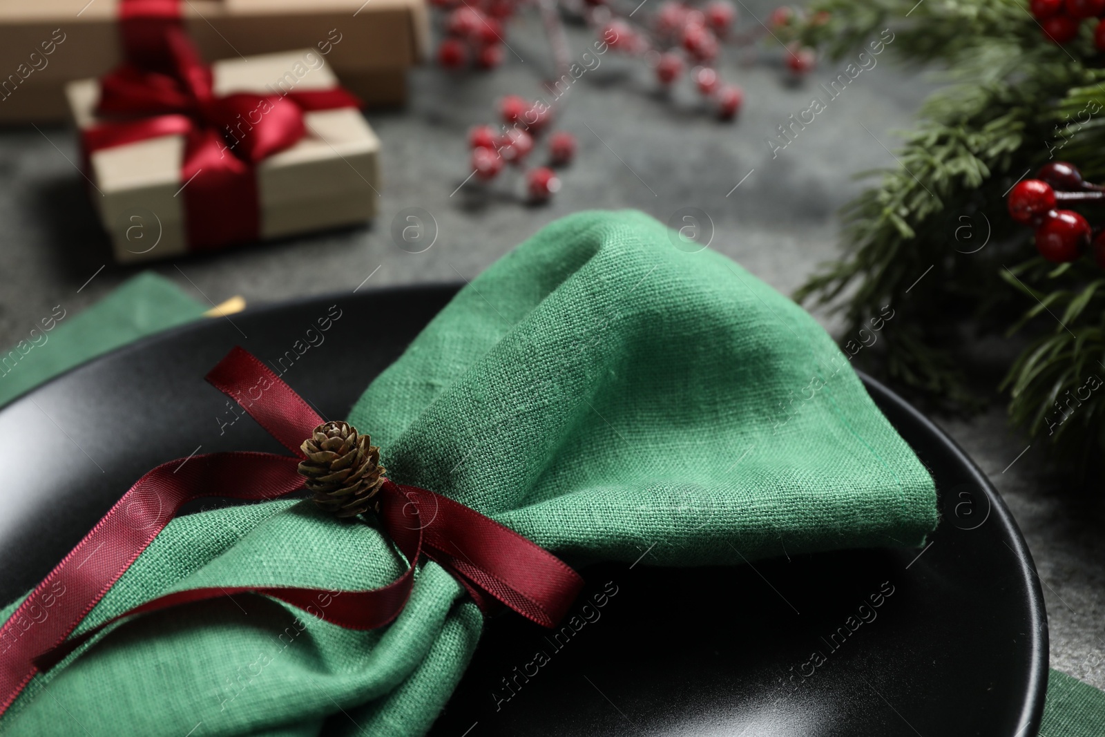 Photo of Plate, napkin and Christmas decor on grey table, closeup