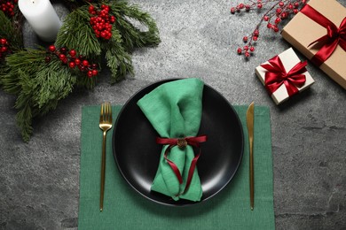 Photo of Christmas place setting with plate, cutlery and festive decor on grey table, flat lay