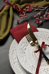 Photo of Plates, cutlery and Christmas decor on black table, above view