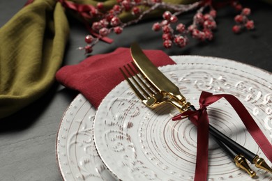 Photo of Plates, cutlery and Christmas decor on black table, closeup