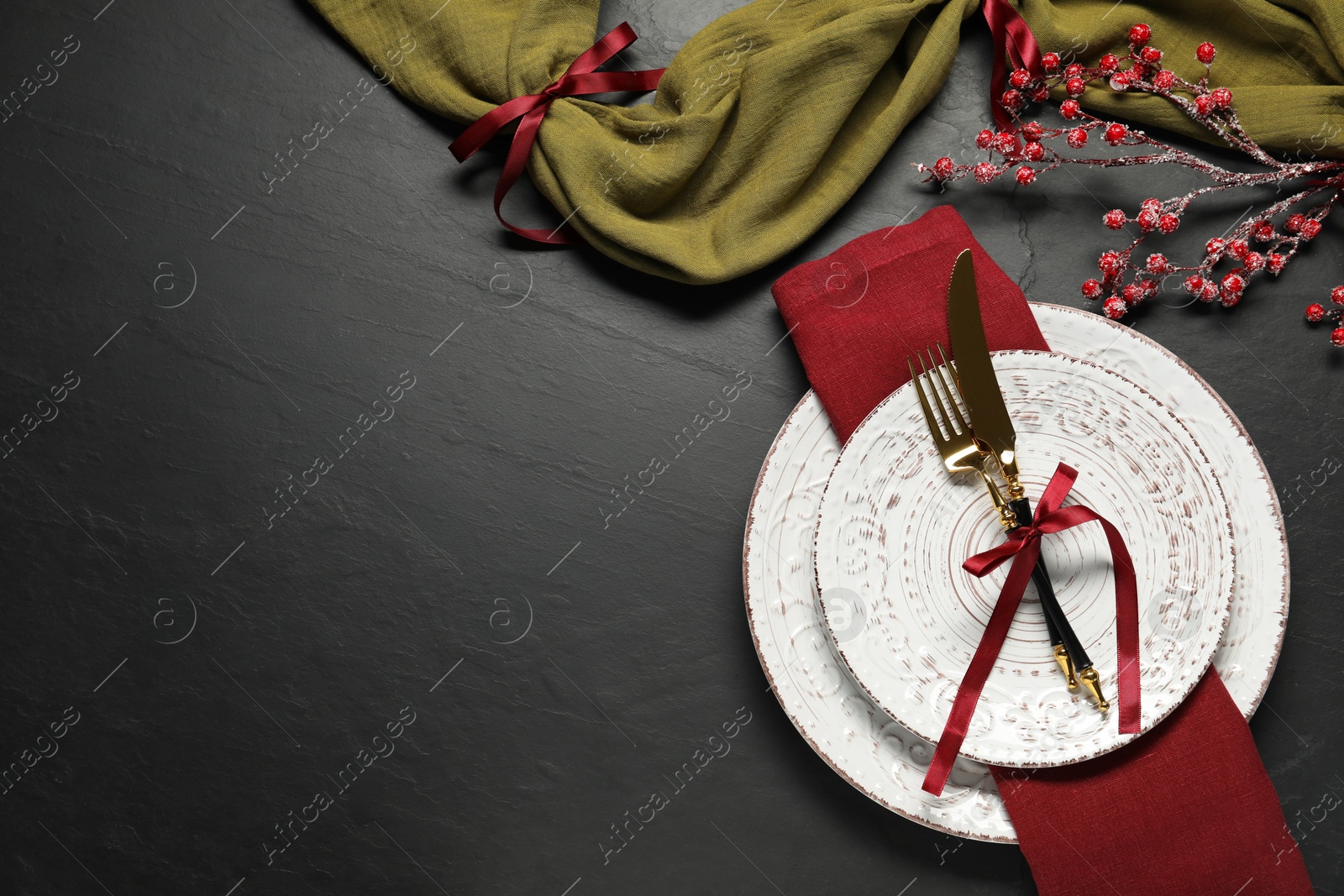 Photo of Christmas place setting with plates, cutlery and festive decor on black table, flat lay. Space for text