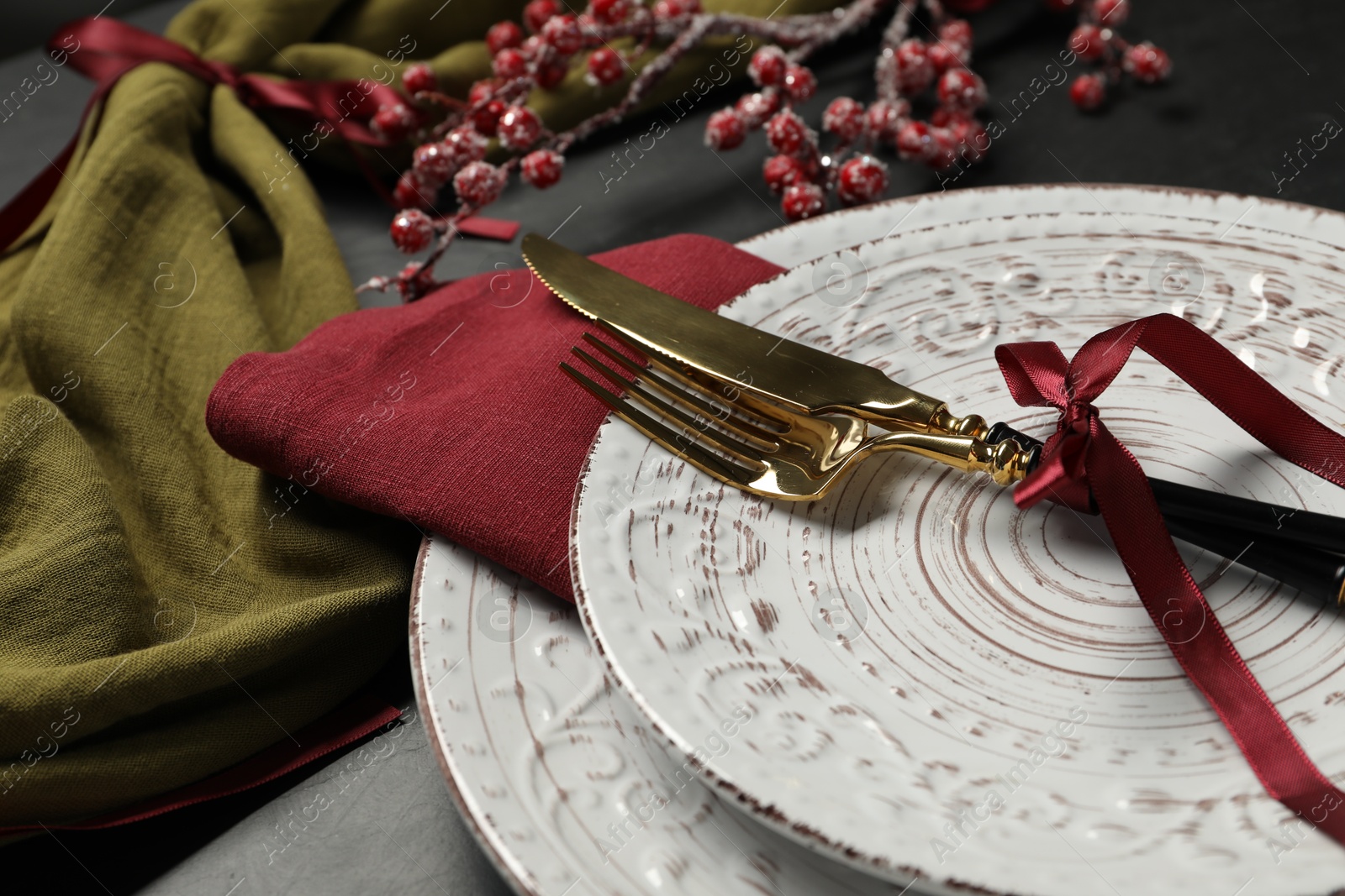 Photo of Plates, cutlery and Christmas decor on black table, closeup