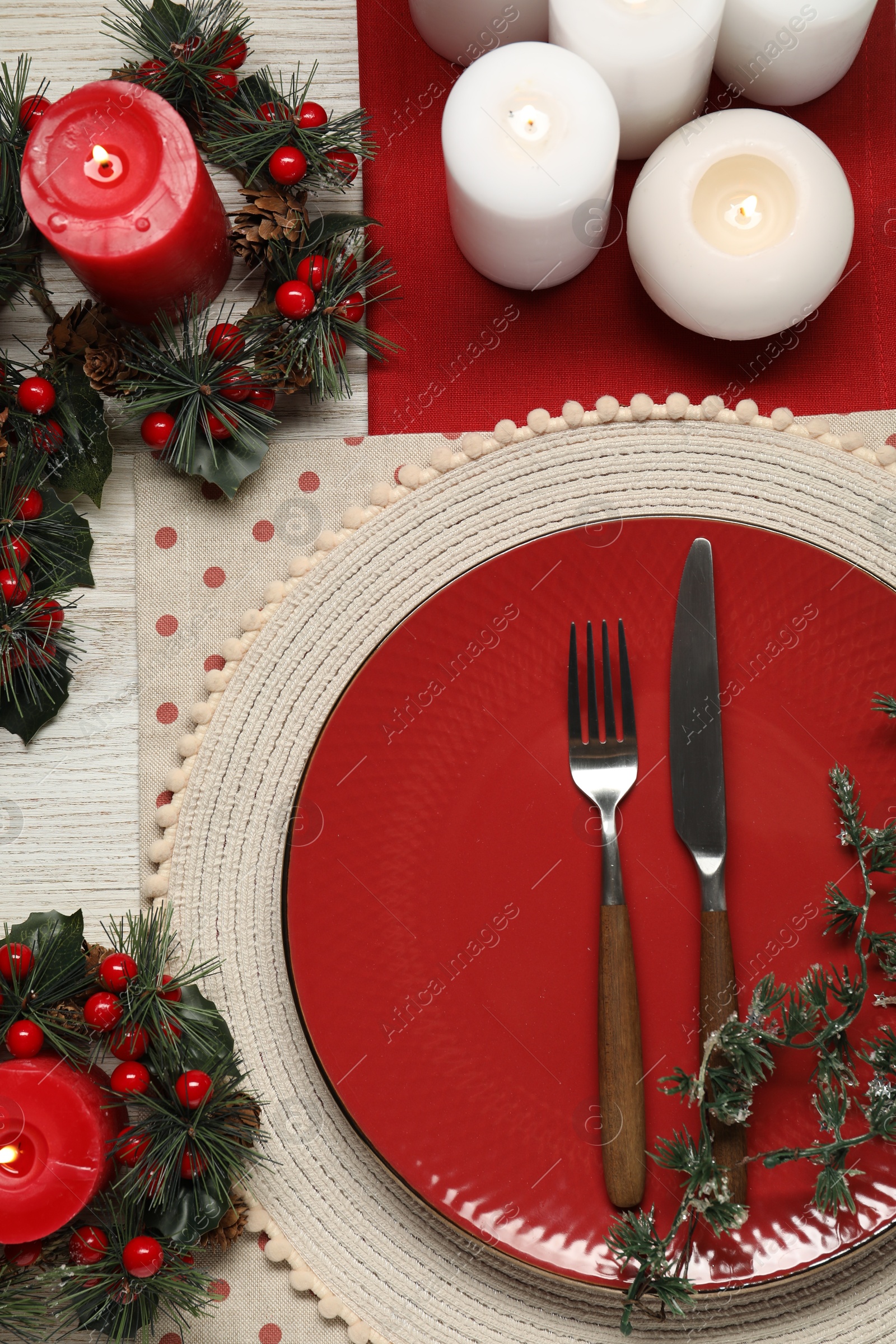 Photo of Christmas place setting with plate, cutlery and festive decor on wooden table, flat lay