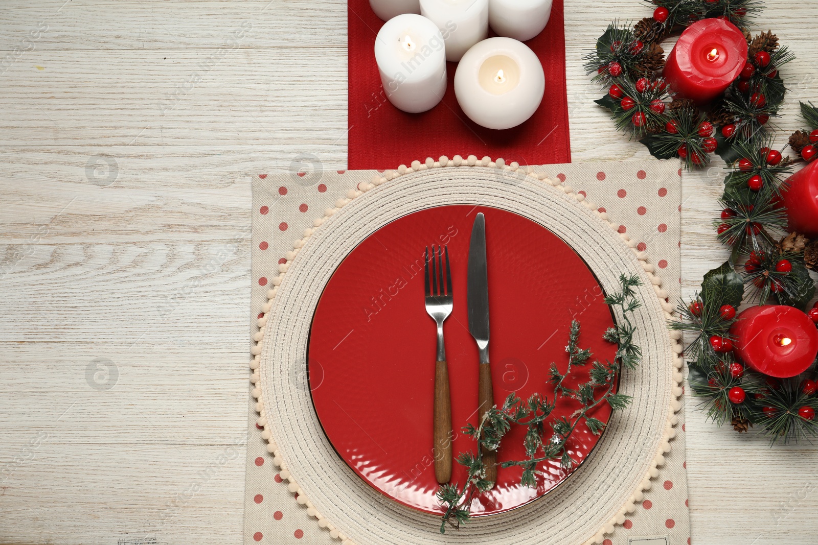 Photo of Christmas place setting with plate, cutlery and festive decor on wooden table, flat lay