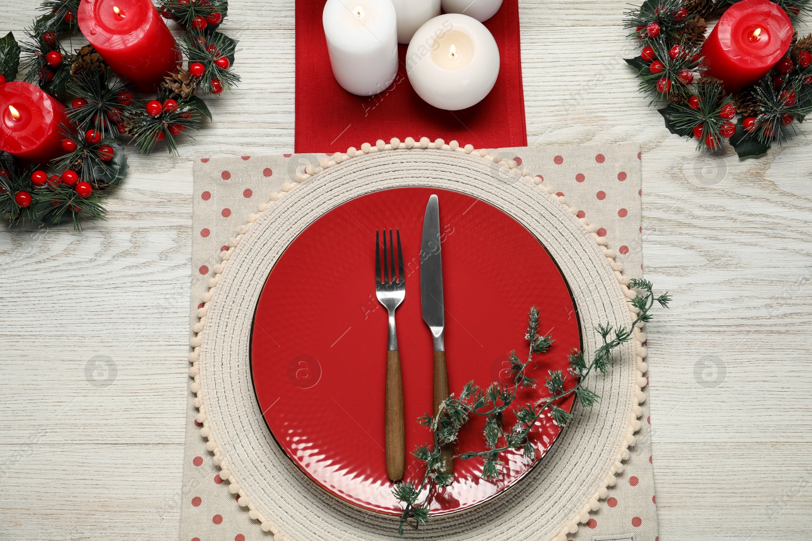 Photo of Christmas place setting with plate, cutlery and festive decor on wooden table, flat lay