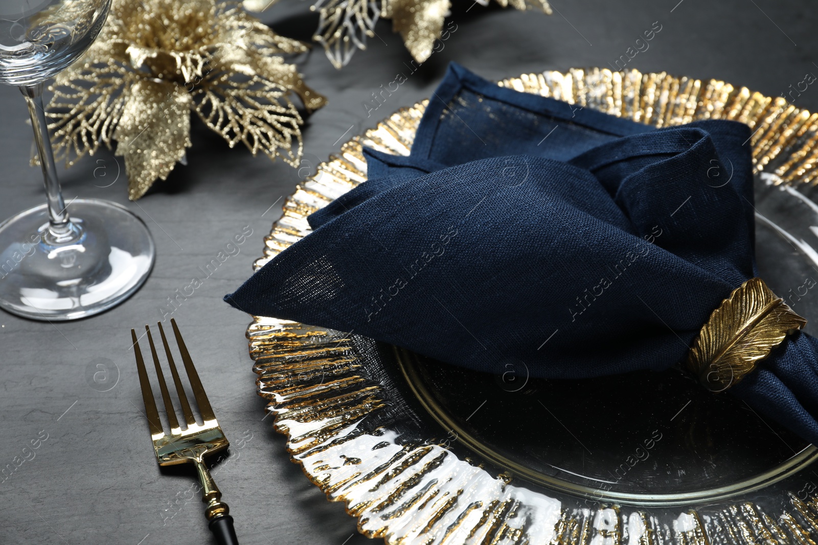 Photo of Plate, fork, napkin and Christmas decor on black table, closeup