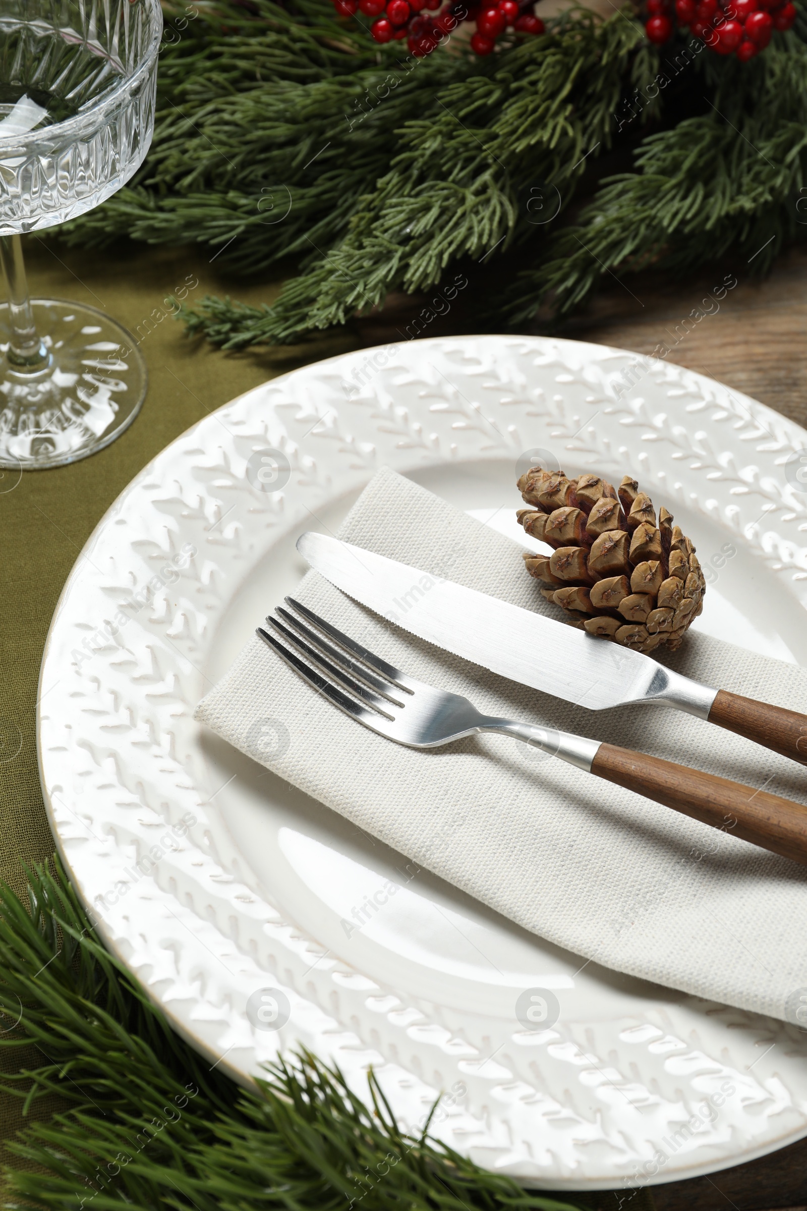 Photo of Christmas place setting with plate, cutlery, glass and festive decor on table