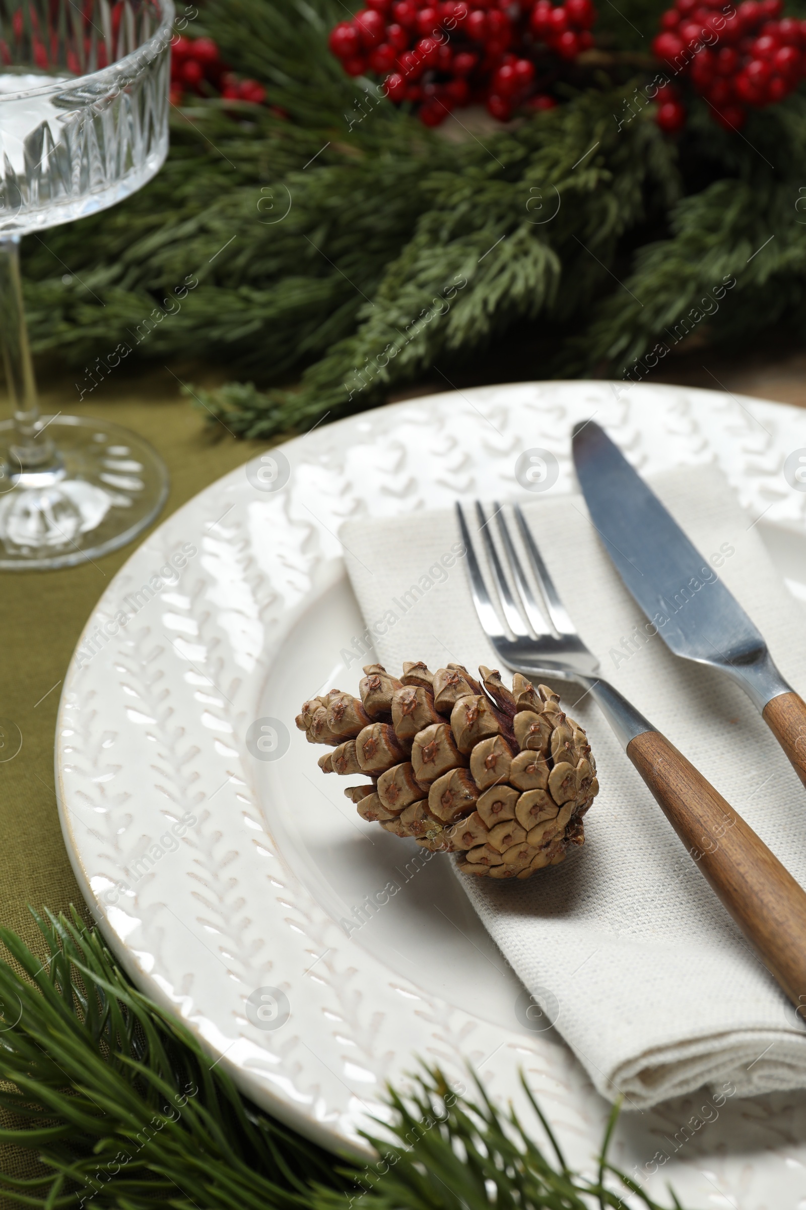 Photo of Christmas place setting with plate, cutlery, glass and festive decor on table, closeup