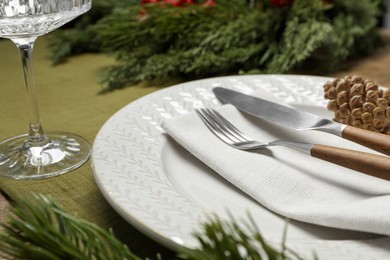 Photo of Christmas place setting with plate, cutlery and festive decor on table, closeup