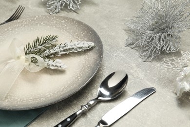 Photo of Christmas place setting with plate, cutlery and festive decor on grey table, closeup