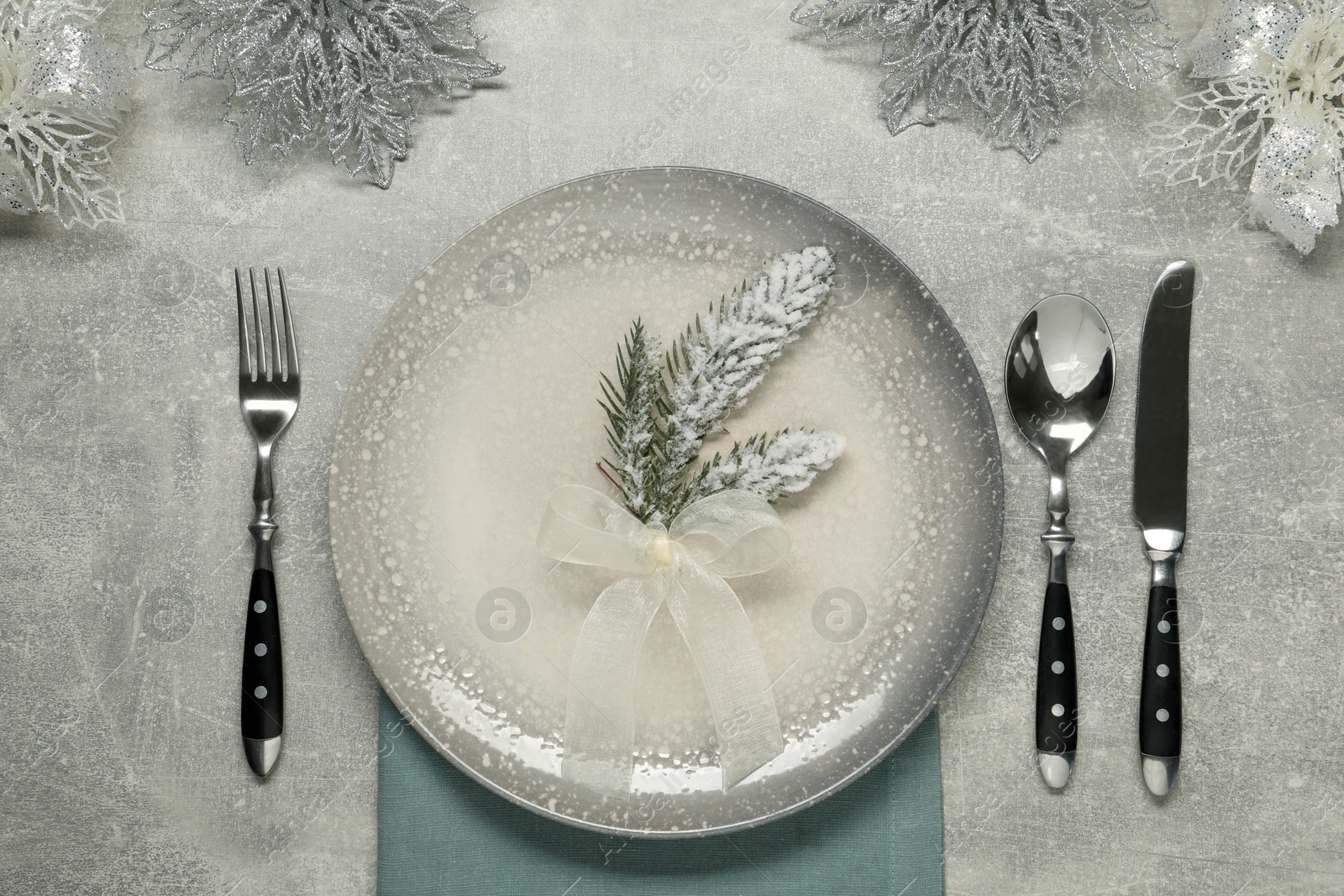 Photo of Christmas place setting with plate, cutlery and festive decor on grey table, flat lay