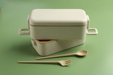 Photo of Plastic lunch box and cutlery on green background