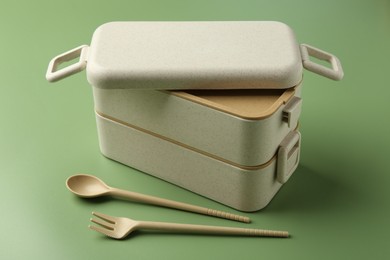 Photo of Plastic lunch box and cutlery on green background