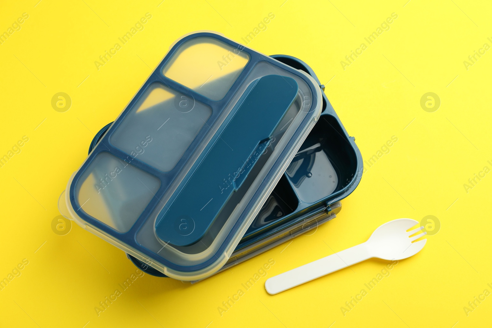 Photo of Empty lunch box and fork on yellow background