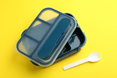 Photo of Empty lunch box and fork on yellow background