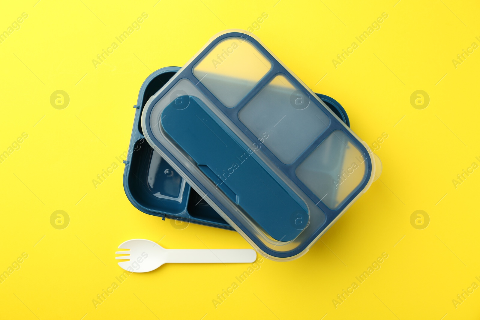 Photo of Empty lunch box and fork on yellow background, flat lay