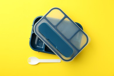 Photo of Empty lunch box and fork on yellow background, flat lay