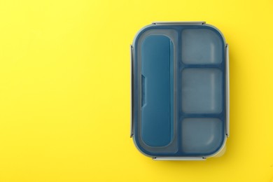 Photo of Empty lunch box on yellow background, top view. Space for text