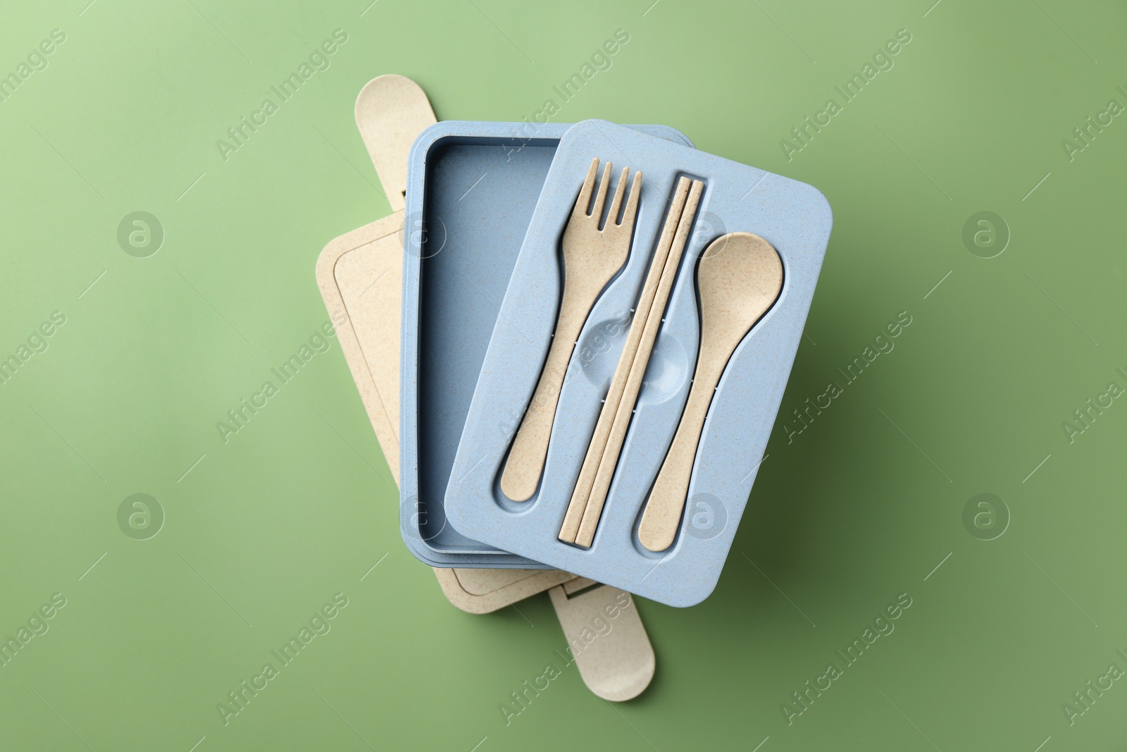 Photo of Empty lunch box with cutlery on green background, top view