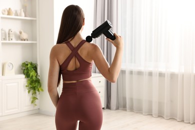 Photo of Woman using percussive massager to relieve trapezius muscle at home, back view. Space for text