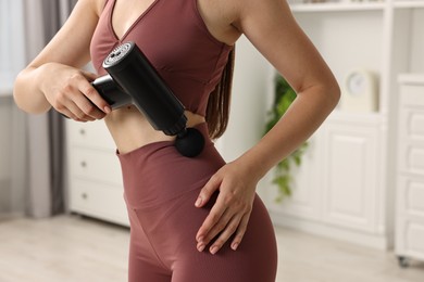 Photo of Woman using percussive massager to relieve abdominal muscles at home, closeup