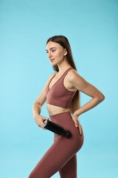 Woman using percussive massager to relax hip muscles on light blue background