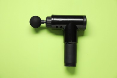 Photo of One black percussive massager on green background, top view