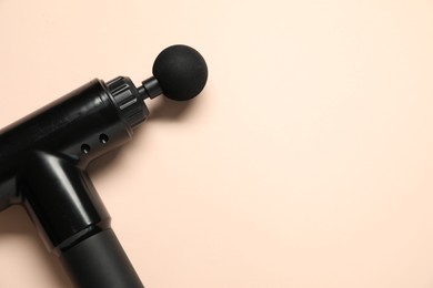 Photo of One black percussive massager on beige background, above view. Space for text