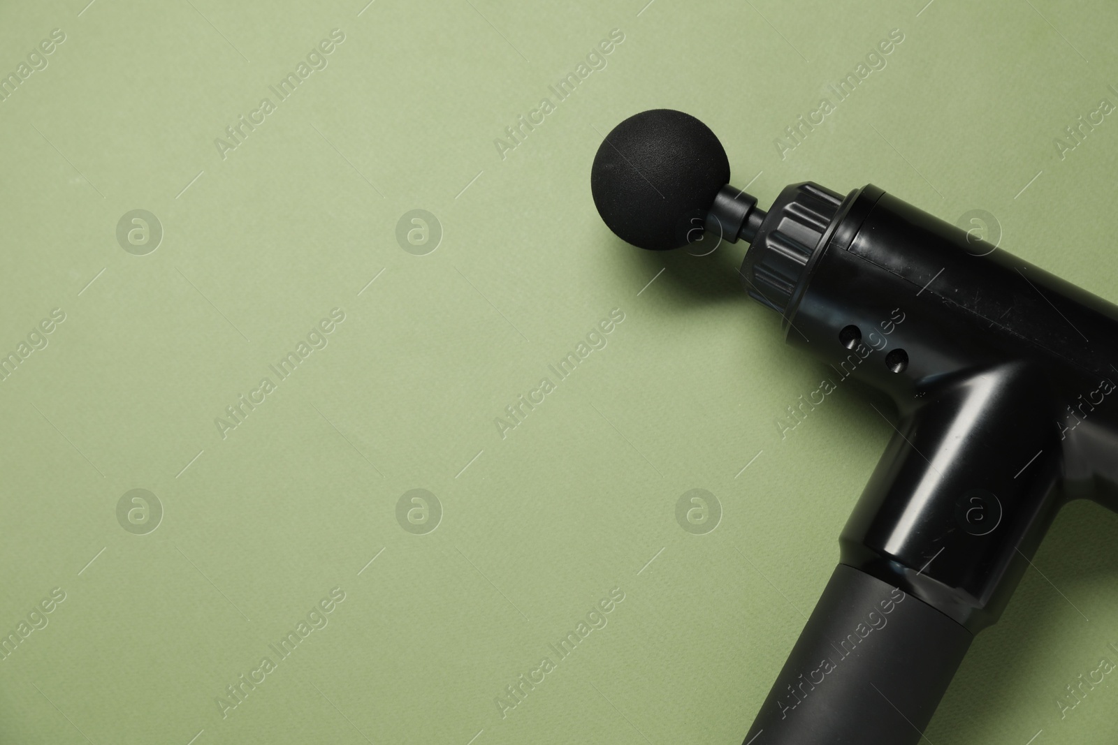 Photo of One black percussive massager on olive background, above view. Space for text