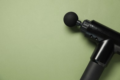 One black percussive massager on olive background, above view. Space for text