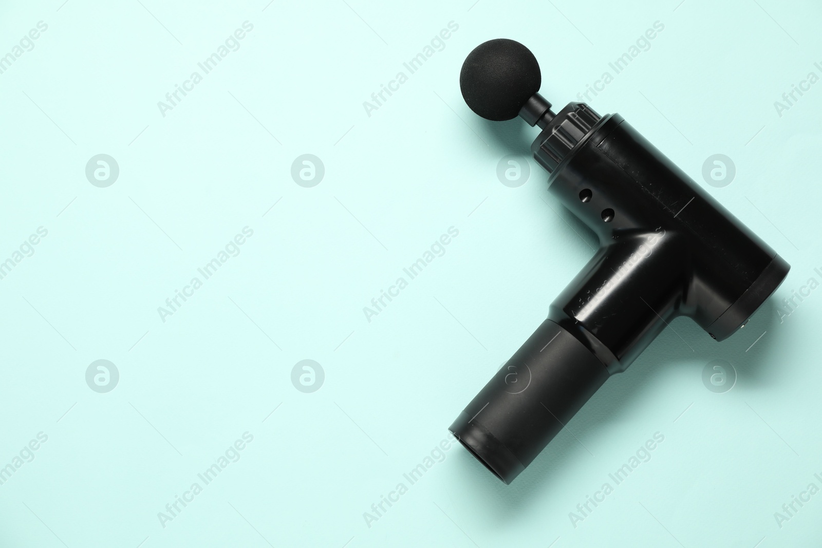 Photo of One black percussive massager on light blue background, top view. Space for text