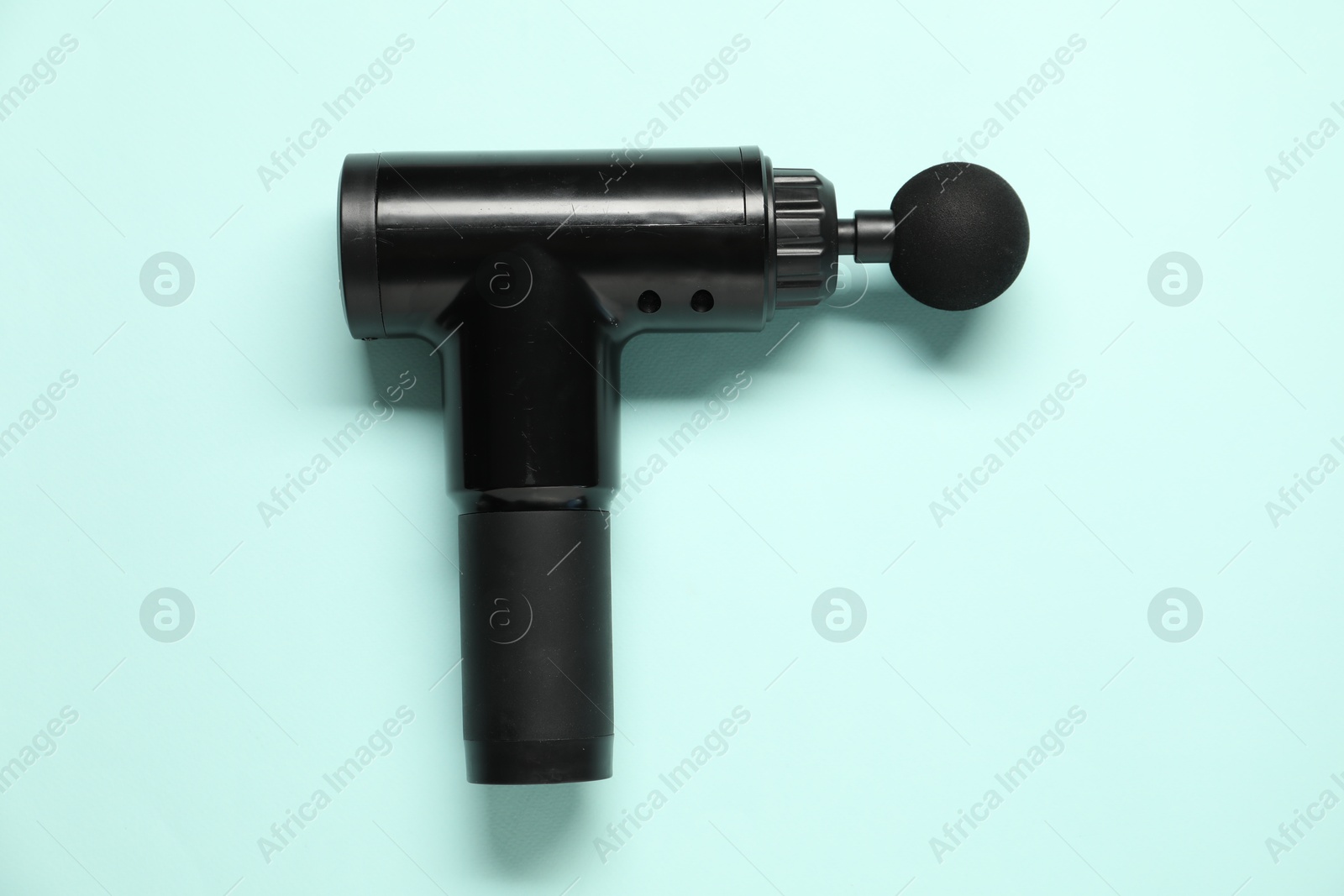 Photo of One black percussive massager on light blue background, top view