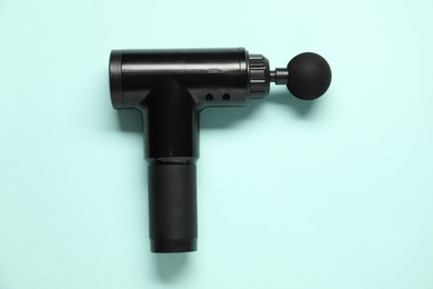 Photo of One black percussive massager on light blue background, top view