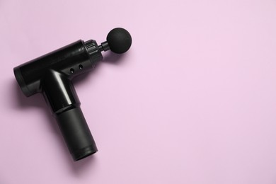 Photo of One black percussive massager on violet background, top view. Space for text