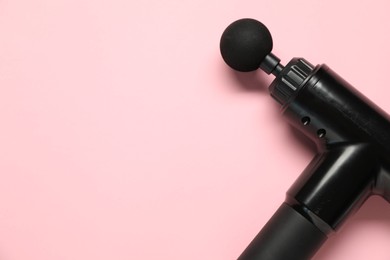 One black percussive massager on pink background, above view. Space for text