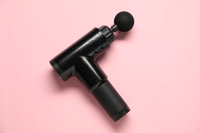 One black percussive massager on pink background, top view