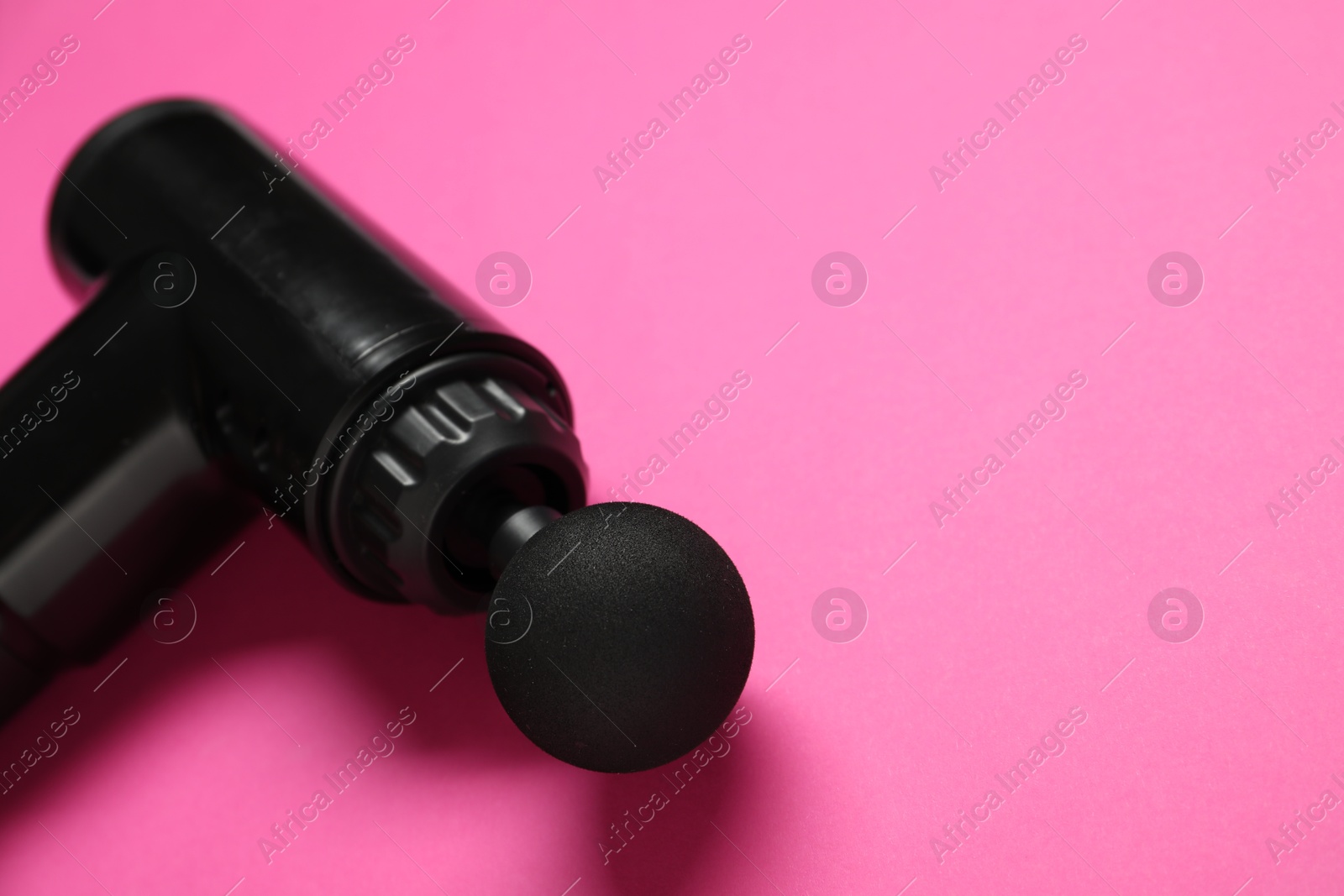 Photo of One black percussive massager on pink background, closeup. Space for text