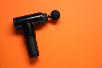 One black percussive massager on orange background, top view. Space for text