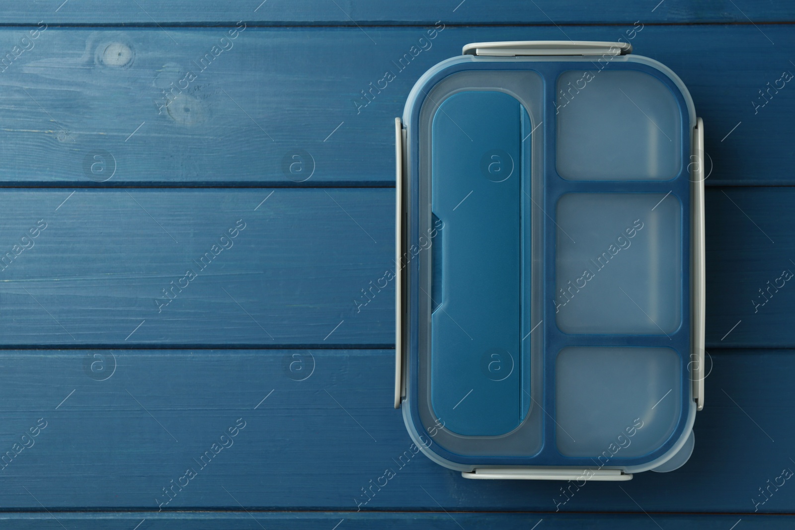 Photo of Empty lunch box on blue wooden table, top view. Space for text