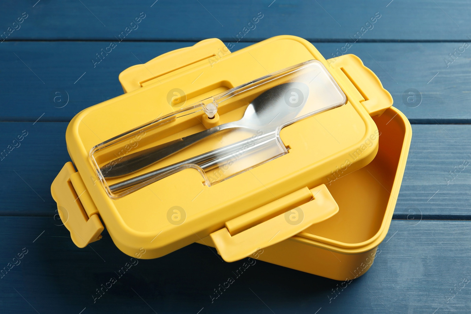 Photo of Yellow lunch box with cutlery on blue wooden table