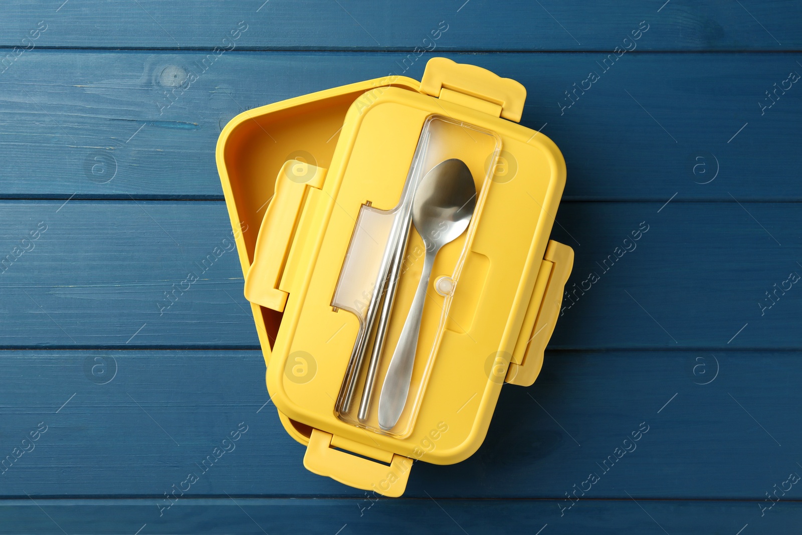 Photo of Yellow lunch box with cutlery on blue wooden table, top view