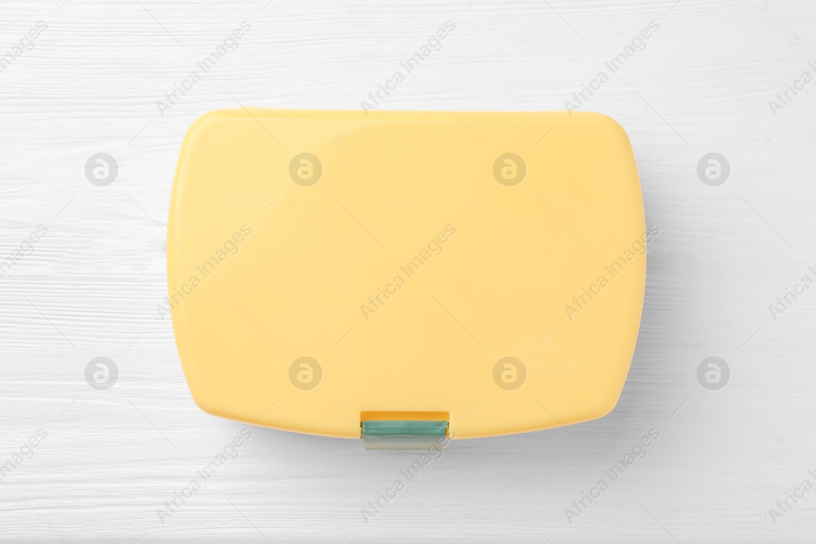 Photo of Yellow lunch box on white wooden table, top view