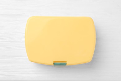 Yellow lunch box on white wooden table, top view