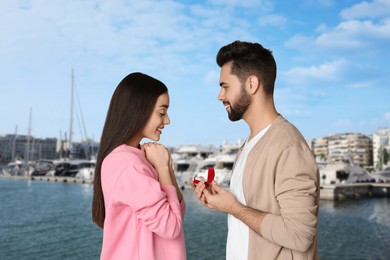 Man with engagement ring making marriage proposal to his girlfriend. Couple against cityscape