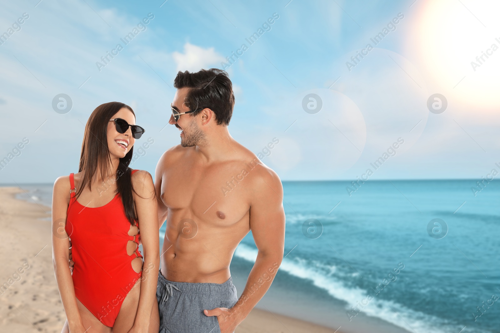 Image of Happy couple enjoying their honeymoon at sea. Newlyweds smiling on sandy beach during sunny day