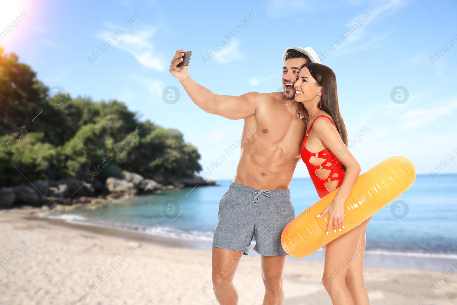 Image of Happy newlyweds taking selfie at sea on honeymoon. Couple smiling on tropical beach during sunny day