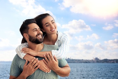 Happy newlyweds enjoying their honeymoon. Couple smiling near sea