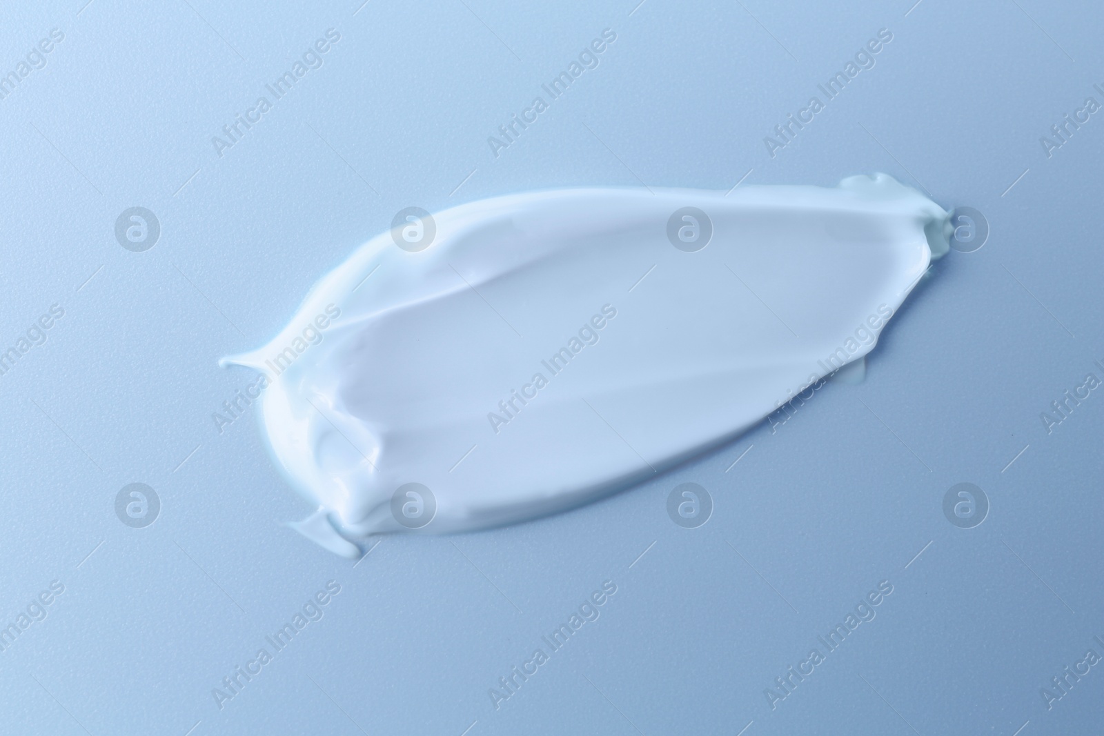 Image of Sample of face cream on light blue background, top view