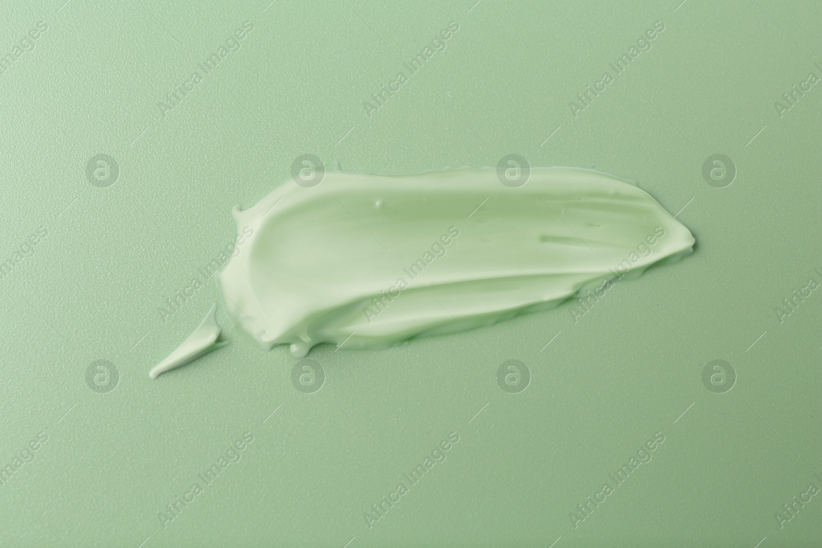 Image of Sample of face cream on green background, top view